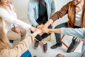 group of people putting hands into the middle of a circle